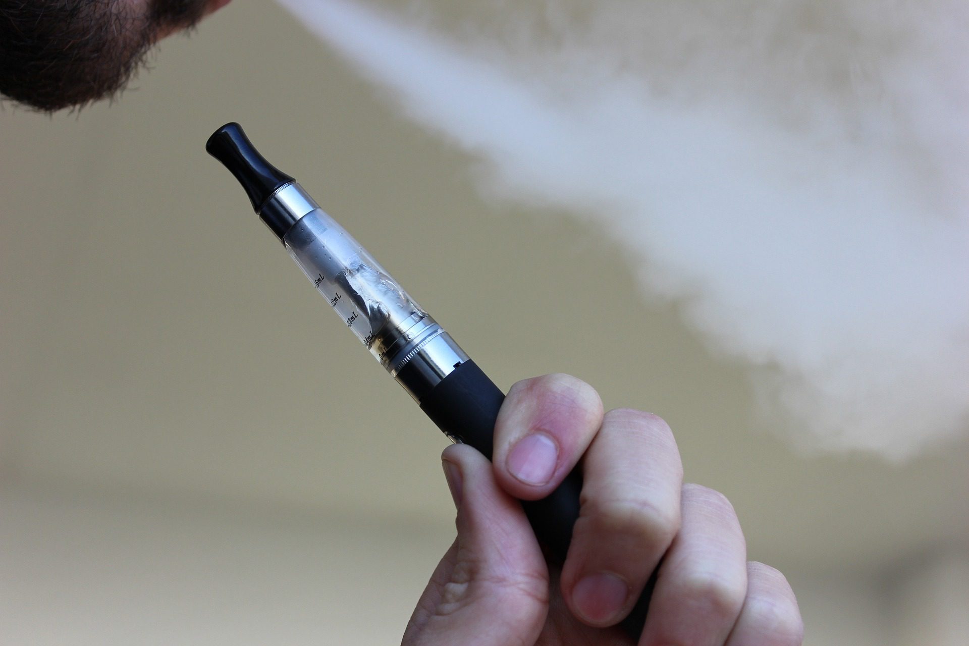 a man smoking an e-cigarette, a potential source of liquid nicotine poisoning